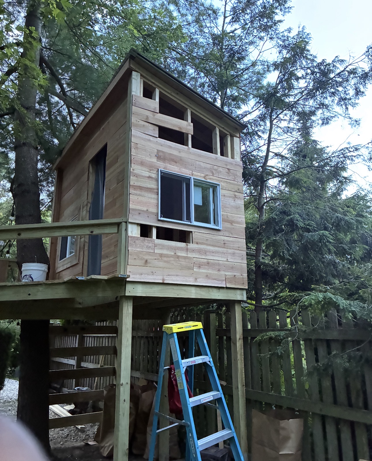 Tree house with siding and a sliding glass window installed