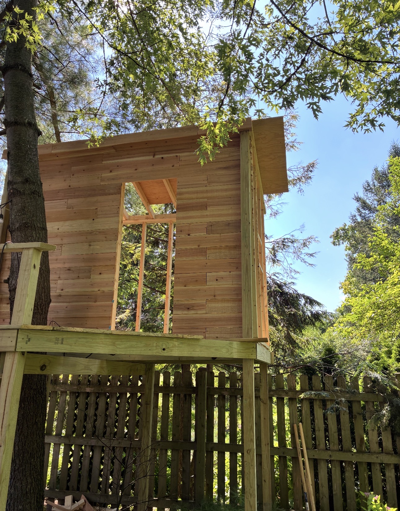 Tree house exterior with wooden siding and door opening